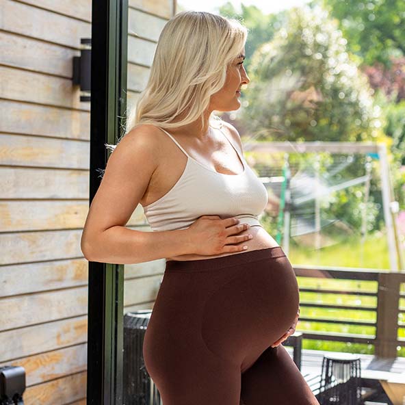 Women holding bump styling mocha coloured BABYGO® Maternity Leggings