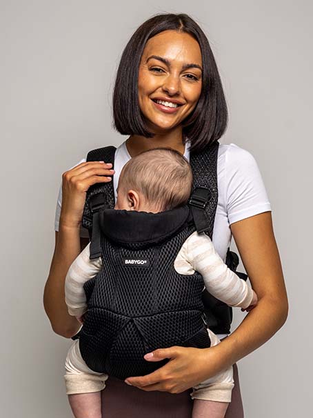 Smiling women carrying baby with black Airmesh™ BABYGO® Baby Carrier