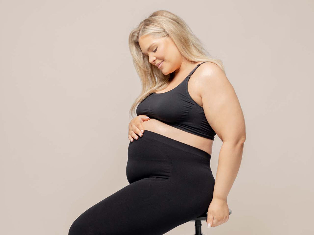 Pregnant woman sitting in the BABYGO® Maternity Bra and over the bump leggings