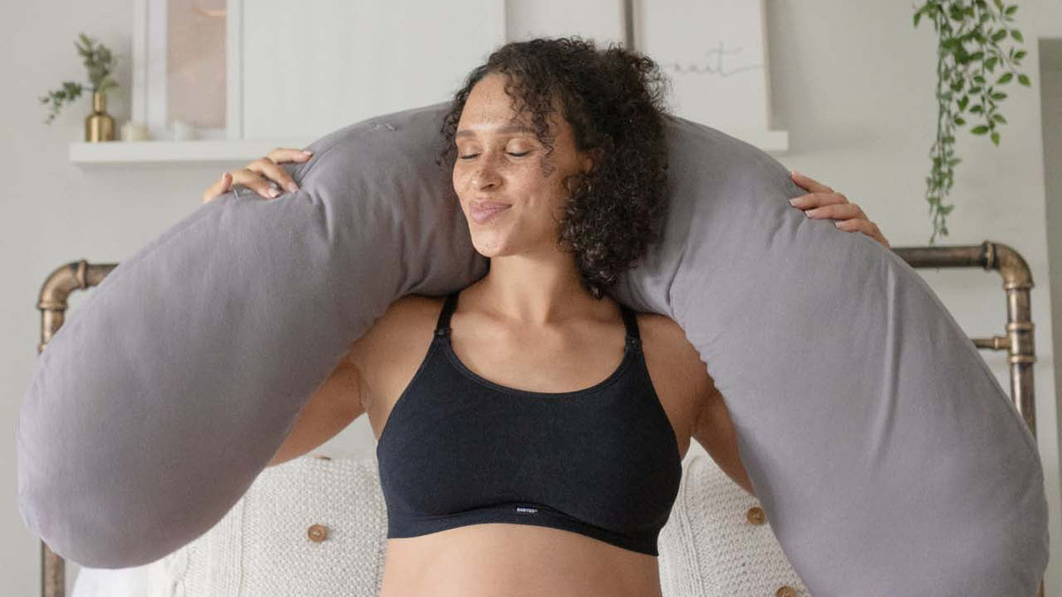 Pregnant mum holding the BABYGO® Moon pregnancy pillow, one of the gifts in this guide