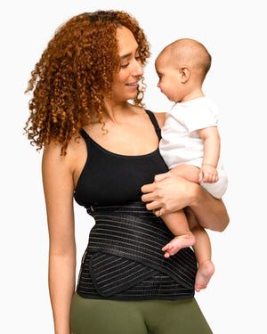woman holding baby wearing postpartum support belt