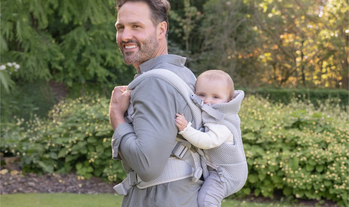 Dad carrying his baby on his back in the grey AirMesh carrier