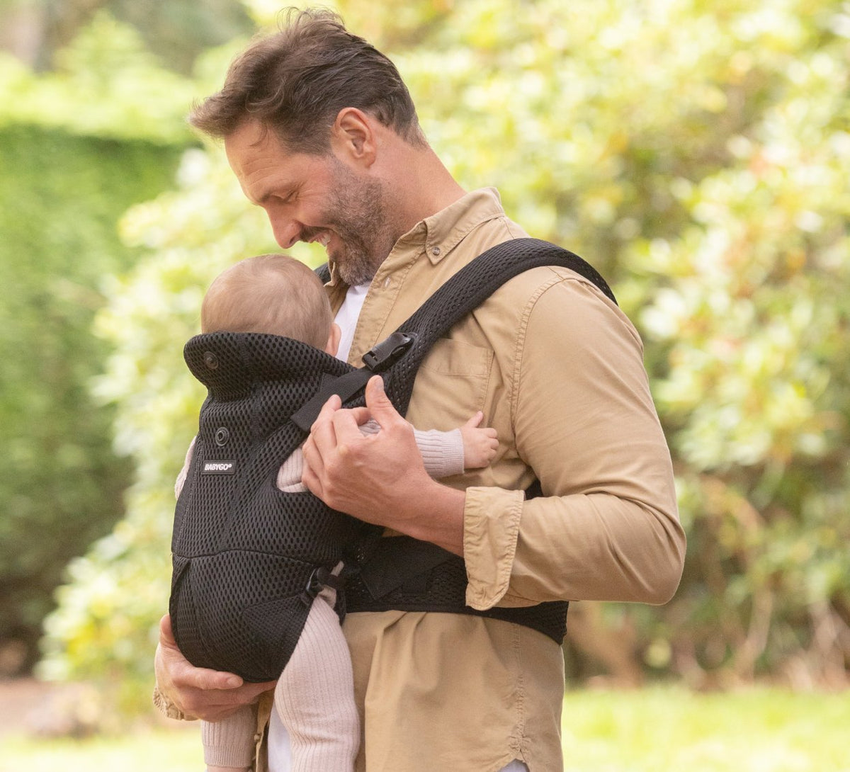 Dad carrying his baby facing in, in the black AirMesh carrier