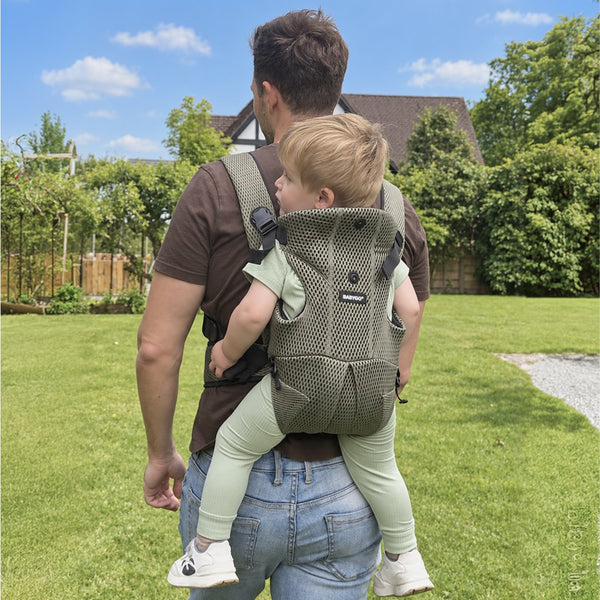 Dad carrying a toddler on his back in the olive AirMesh carrier