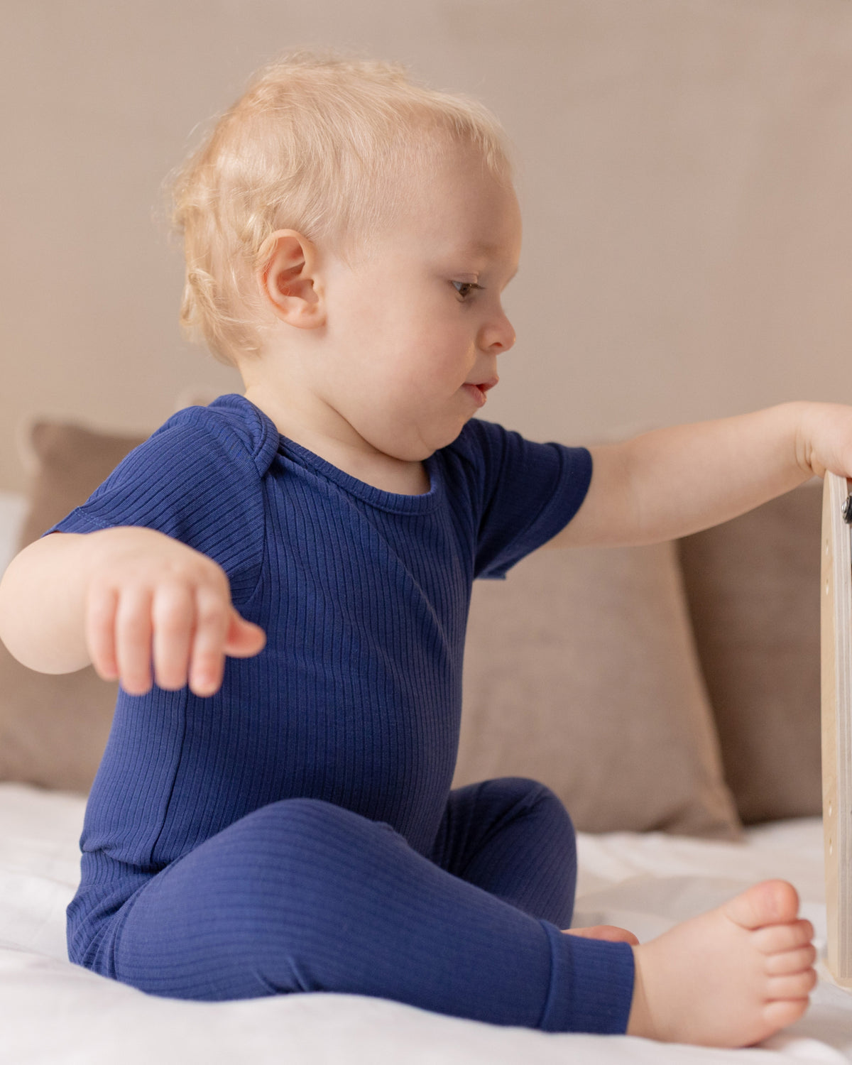 Baby sitting in a navy ribbed short sleeve bodysuit