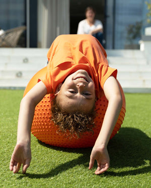 child on orange sensory ball