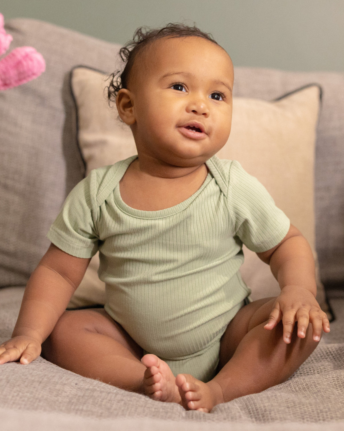 Baby sitting in a sage ribbed short sleeve bodysuit