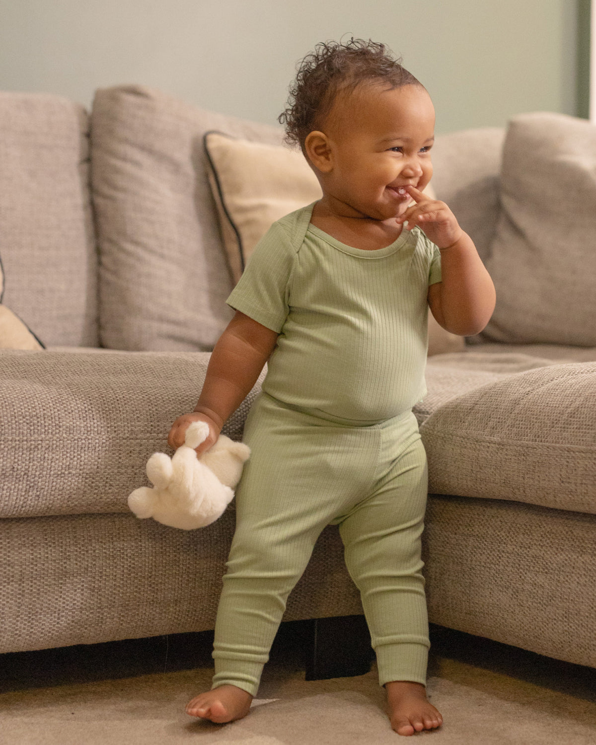 Baby standing in a sage short sleeve bodysuit and leggings