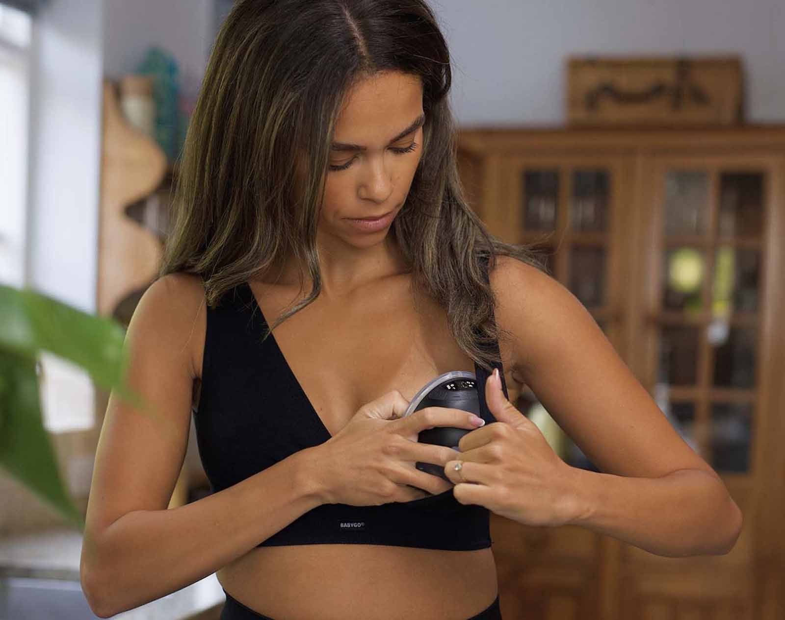 A mother positioning the Air pump inside her nursing bra in the kitchen.