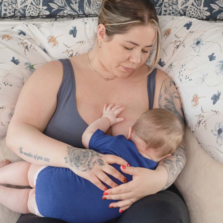 A mother feeding her baby with the pillow supporting them.